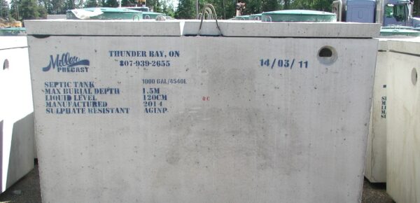 Concrete septic tank by Miller Precast in Thunder Bay, Ontario. Specifications include capacity, dimensions, and manufacturing date. Surrounded by greenery and industrial equipment.