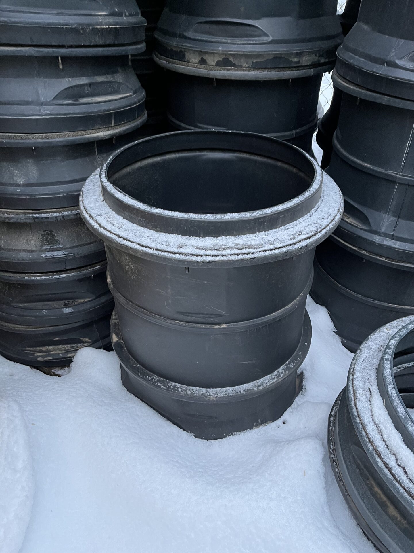 Large black containers stacked in a snowy outdoor setting, dusted with frost, creating an industrial yet serene winter scene.